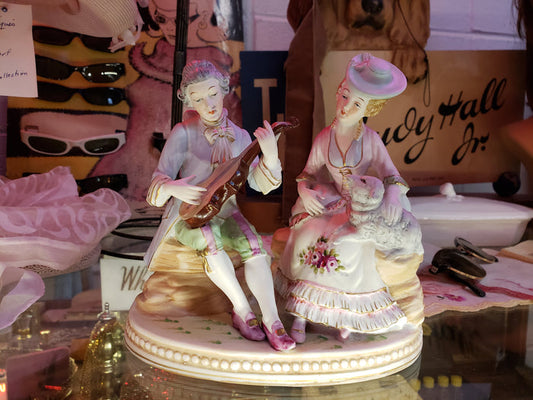 Man playing instrument to Lady holding Sheep figurine