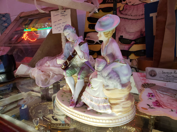 Man playing instrument to Lady holding Sheep figurine